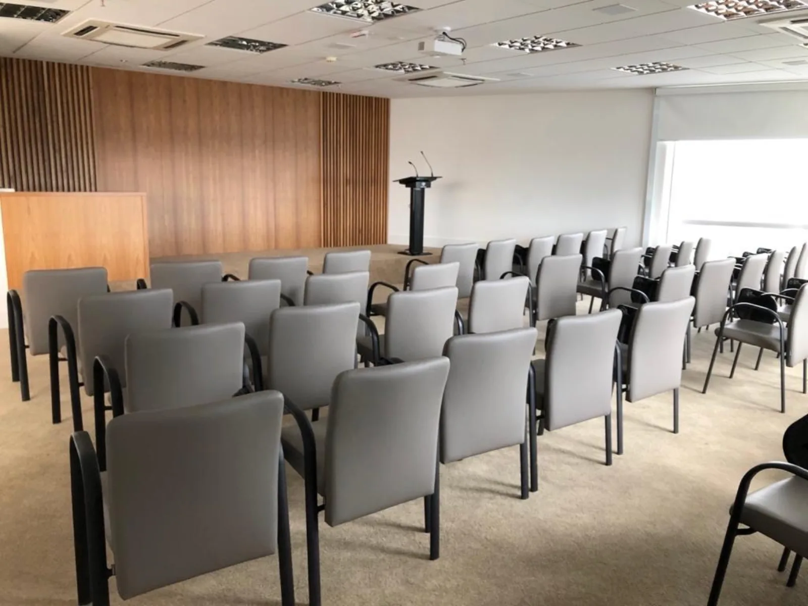 Auditório da Eureka em Campinas visto do fundo, com palco, púlpito e parede ripada de madeira