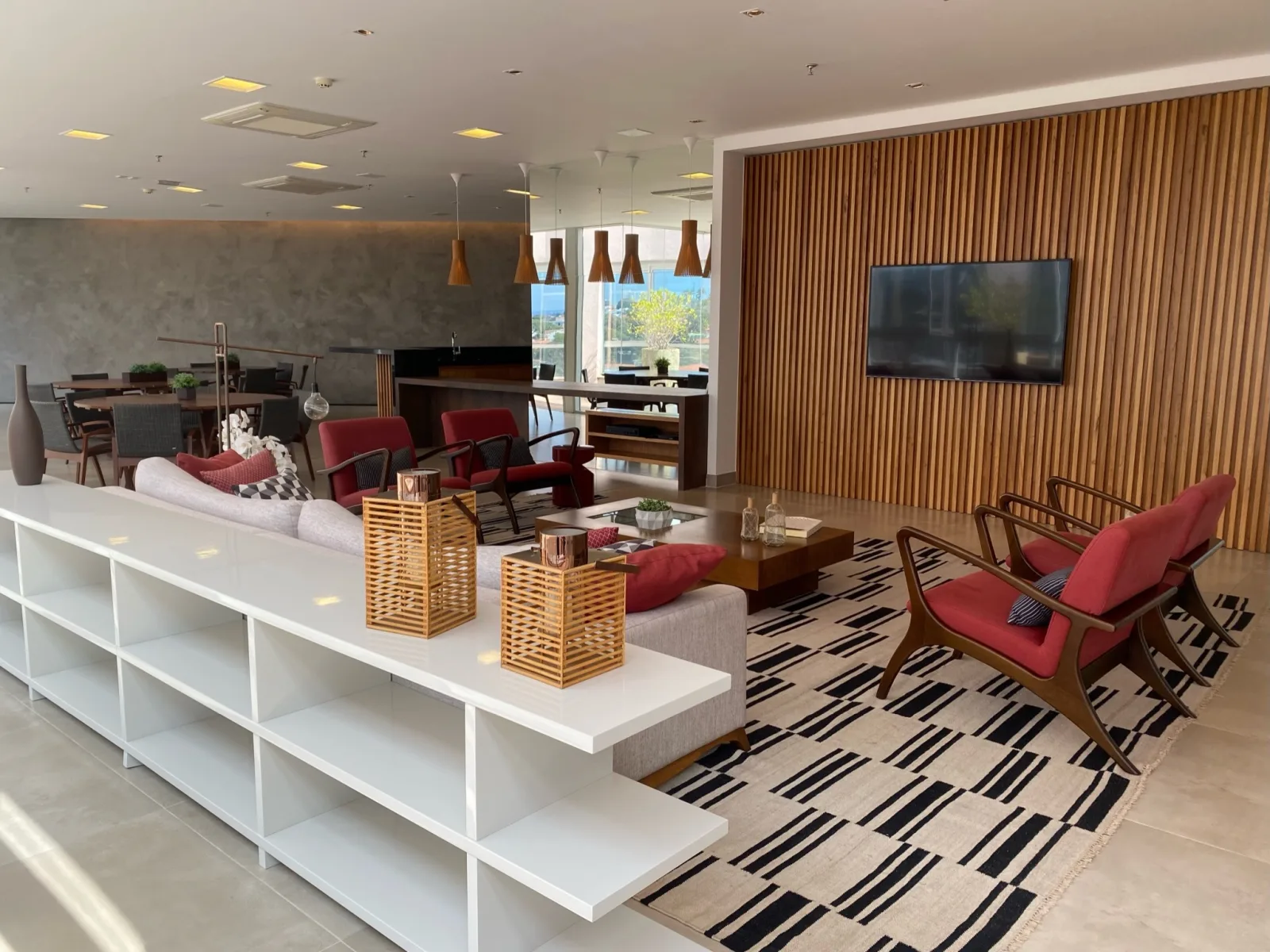 Foyer da Eureka em Campinas com sofás, poltronas, TV na parede ripada e mesas ao fundo, usado para credenciamento e coffee break
